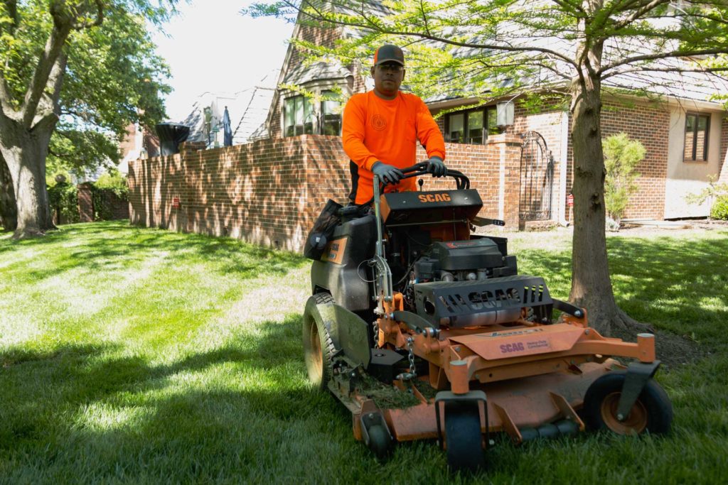 A man in glasses mows a lawn