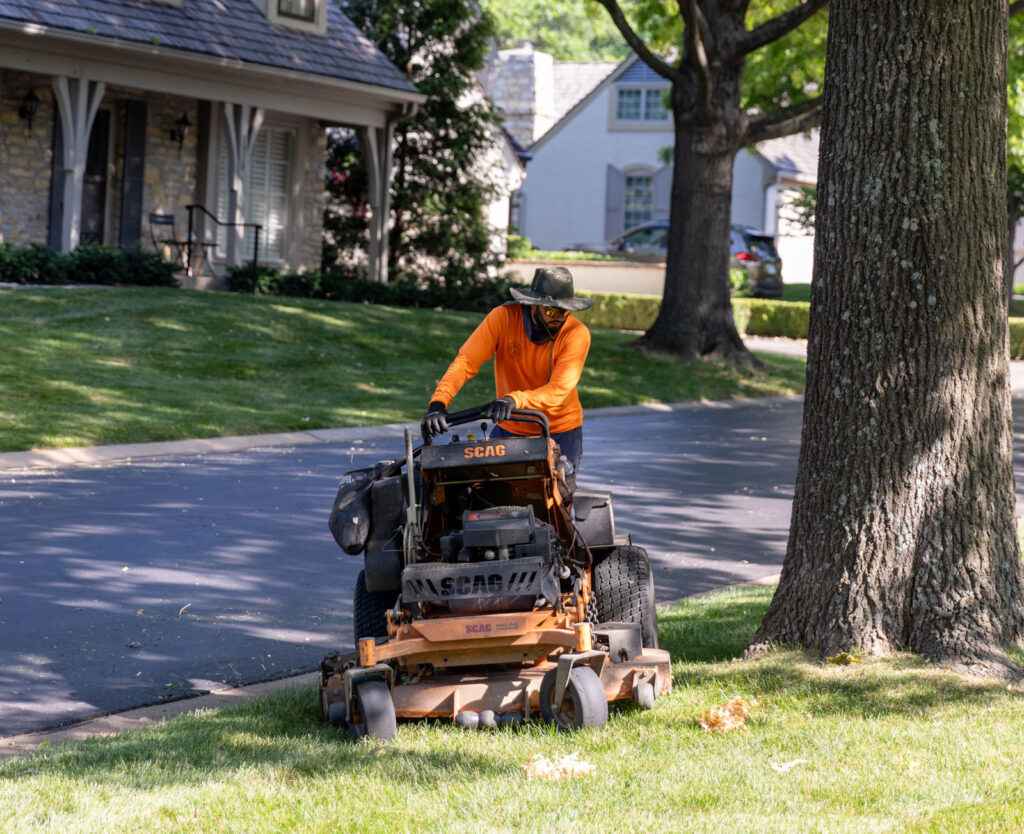 A man on a riding mower performs an HOA grass cutting service in Kansas City